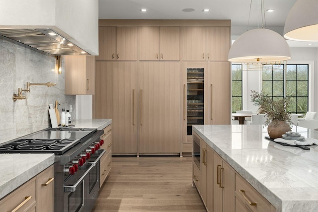 kitchen featuring range with two ovens, custom exhaust hood, light brown cabinets, and light stone counters