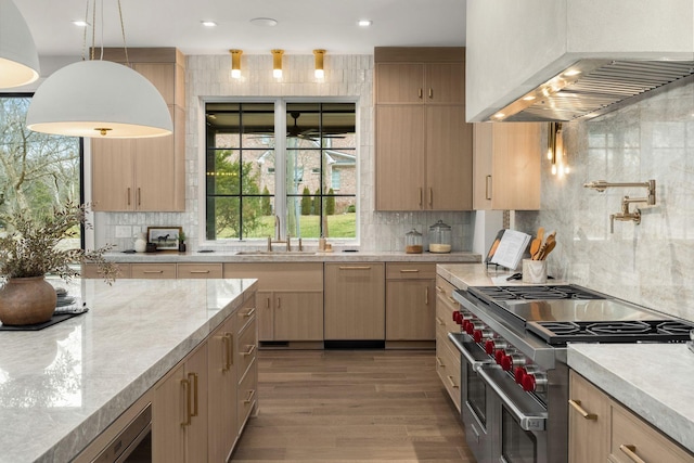 kitchen with pendant lighting, sink, range with two ovens, custom exhaust hood, and light brown cabinets