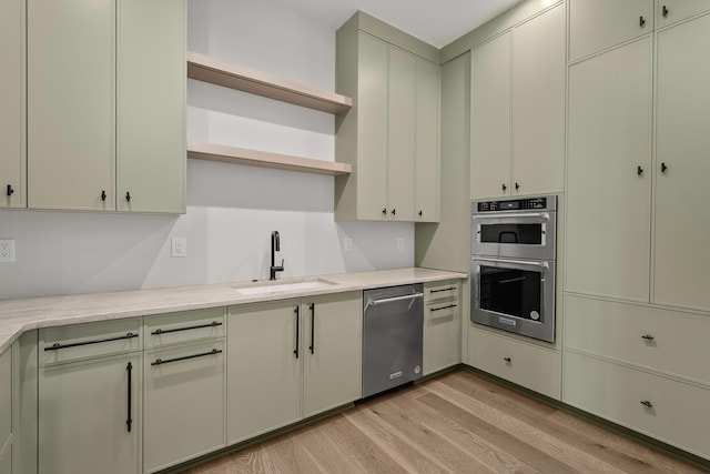 kitchen featuring sink, stainless steel appliances, light hardwood / wood-style floors, and light stone countertops