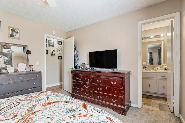 bedroom featuring baseboards, a textured ceiling, ensuite bathroom, and carpet