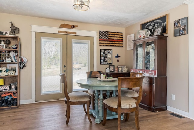 dining area featuring wood finished floors, french doors, visible vents, and a textured ceiling