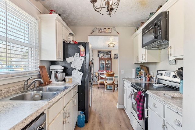 kitchen featuring a sink, stainless steel appliances, light countertops, light wood-style floors, and a textured ceiling