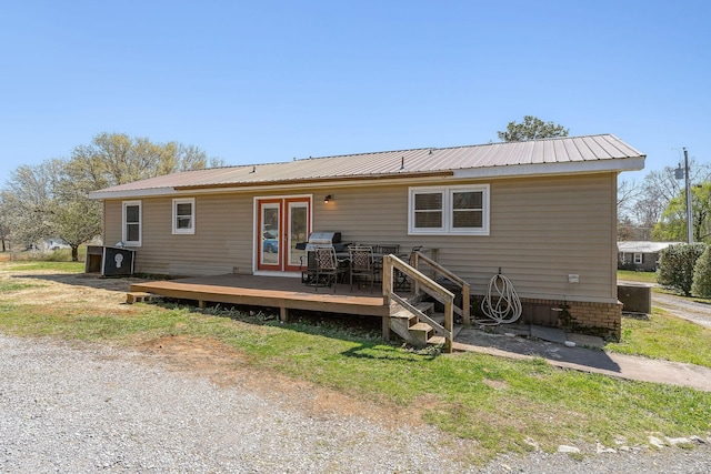rear view of property featuring french doors, metal roof, and a deck
