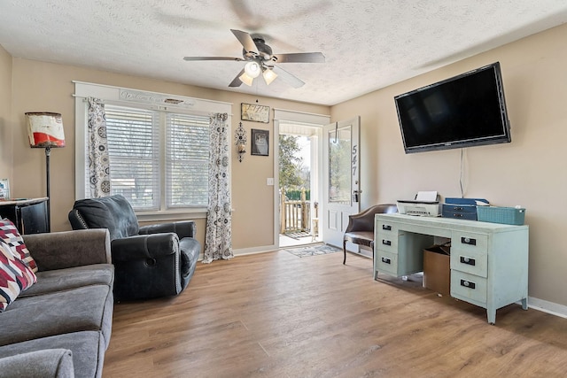 living room featuring baseboards, a textured ceiling, ceiling fan, and wood finished floors
