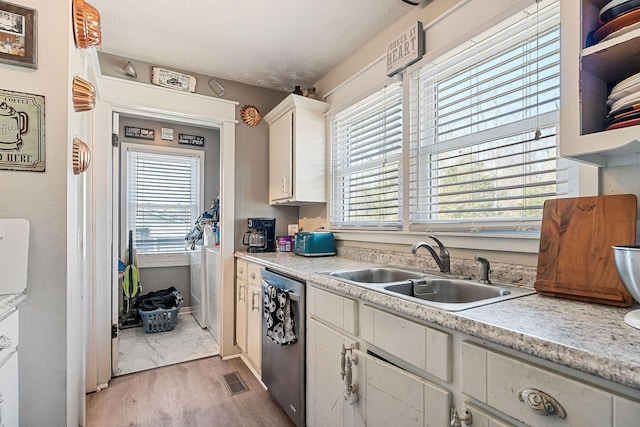 kitchen with a sink, stainless steel dishwasher, light wood-style flooring, and light countertops