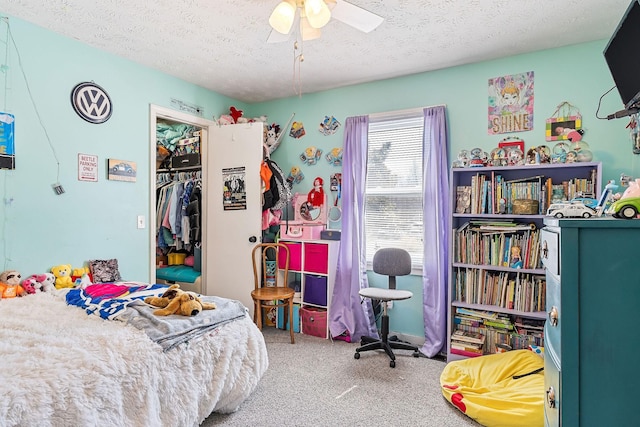 carpeted bedroom with a closet, a textured ceiling, a walk in closet, and ceiling fan