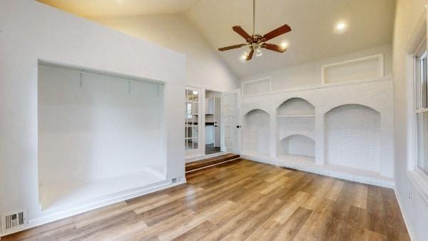 unfurnished living room featuring ceiling fan, high vaulted ceiling, and wood-type flooring