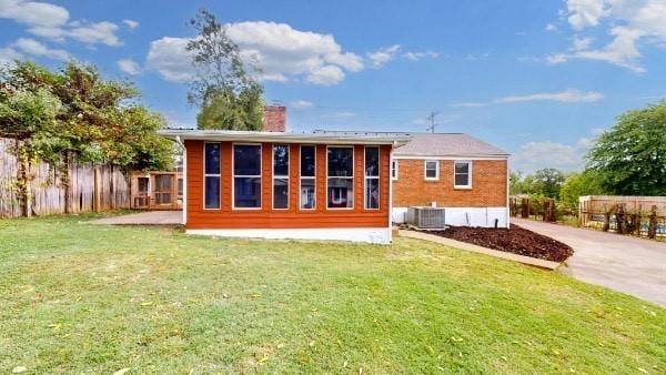 rear view of property featuring a yard and central AC