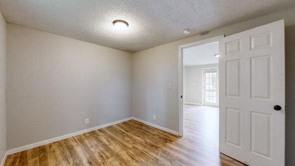 empty room featuring a textured ceiling and light hardwood / wood-style flooring