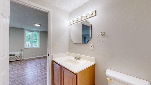 bathroom featuring wood-type flooring, a textured ceiling, toilet, and vanity