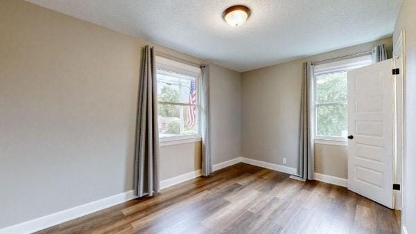 unfurnished room with dark hardwood / wood-style floors and a textured ceiling