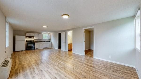 unfurnished living room featuring an AC wall unit and light hardwood / wood-style floors