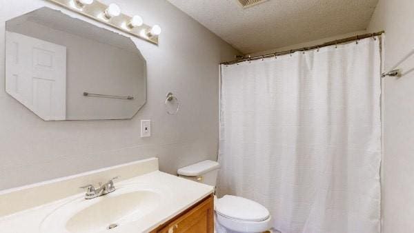 bathroom featuring vanity, toilet, and a textured ceiling