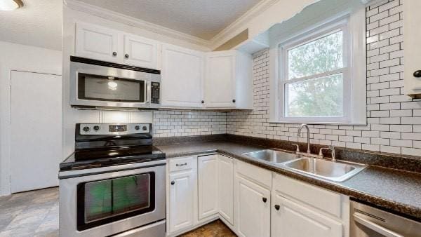 kitchen featuring white cabinetry, sink, ornamental molding, backsplash, and stainless steel appliances