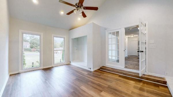 unfurnished room featuring hardwood / wood-style flooring, high vaulted ceiling, and ceiling fan