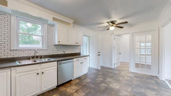 kitchen with a textured ceiling, white cabinets, sink, backsplash, and stainless steel dishwasher