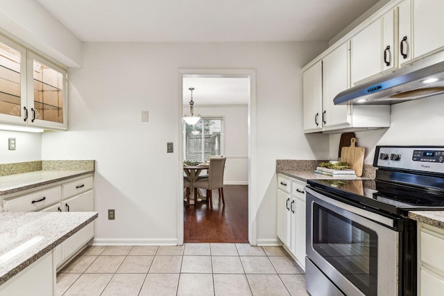 kitchen featuring light tile patterned flooring, hanging light fixtures, white cabinets, and stainless steel range with electric cooktop