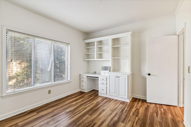 unfurnished office with crown molding, dark wood-type flooring, and built in desk