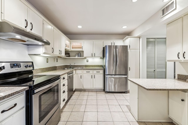 kitchen featuring light stone countertops, white cabinetry, light tile patterned floors, and stainless steel appliances