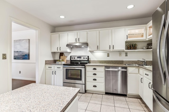 kitchen featuring white cabinets, stainless steel appliances, sink, light tile patterned flooring, and light stone counters