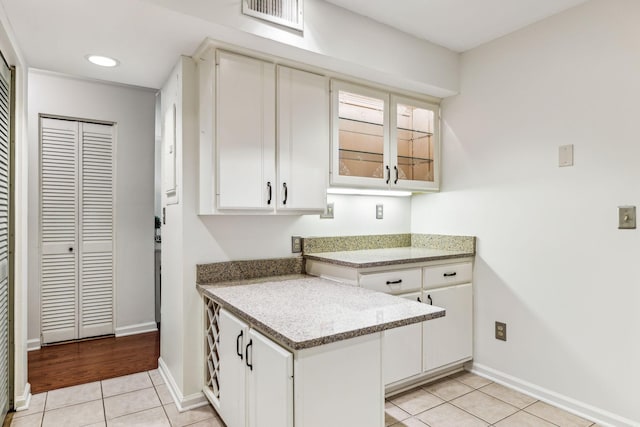 kitchen with light stone counters, white cabinetry, kitchen peninsula, and light tile patterned flooring