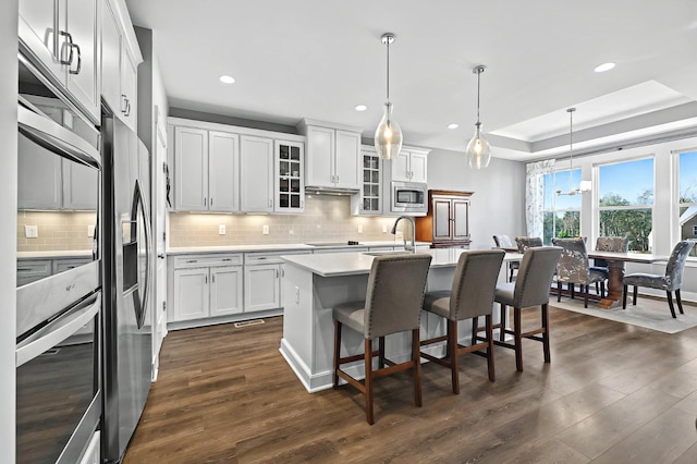 kitchen with pendant lighting, an island with sink, white cabinetry, and appliances with stainless steel finishes