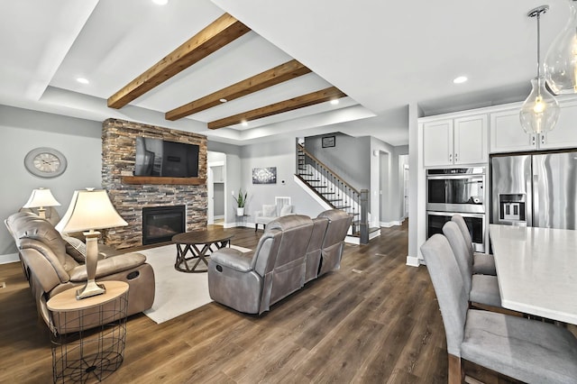 living room with dark hardwood / wood-style floors, a stone fireplace, and beam ceiling