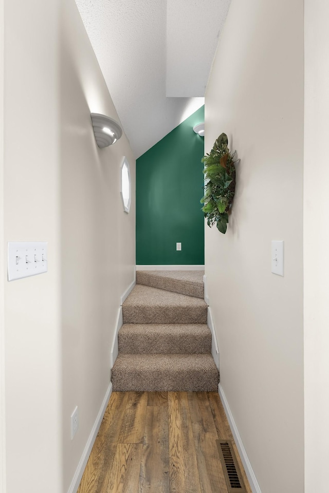 staircase with hardwood / wood-style flooring and a textured ceiling