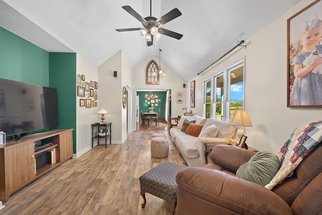 living room featuring ceiling fan, a textured ceiling, light hardwood / wood-style flooring, and lofted ceiling