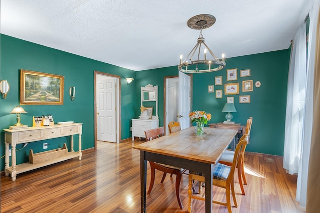 dining area featuring hardwood / wood-style floors, a chandelier, and a textured ceiling