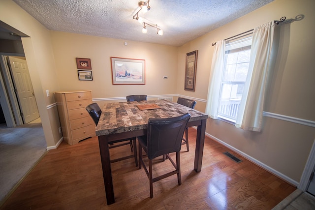 dining room featuring hardwood / wood-style flooring, rail lighting, and a textured ceiling