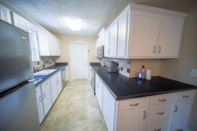 kitchen featuring appliances with stainless steel finishes, sink, tasteful backsplash, white cabinetry, and a textured ceiling