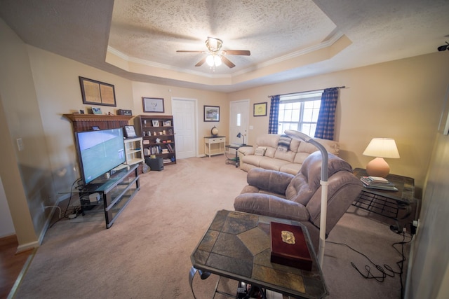 carpeted living room featuring ceiling fan, a raised ceiling, ornamental molding, and a textured ceiling