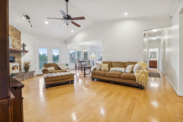 living room with light wood-type flooring, vaulted ceiling, ceiling fan with notable chandelier, and ornamental molding