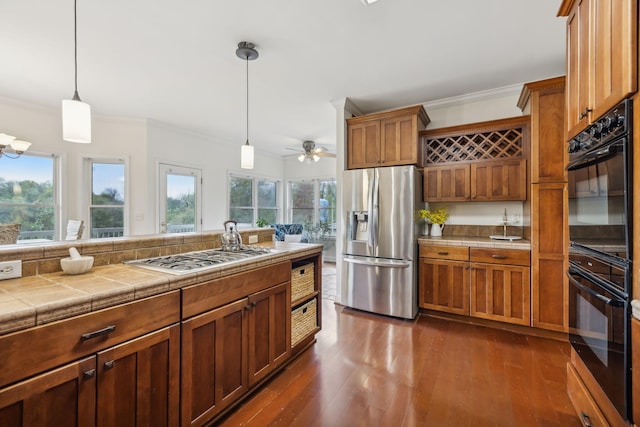 kitchen featuring crown molding, tile counters, decorative light fixtures, stainless steel appliances, and dark hardwood / wood-style floors