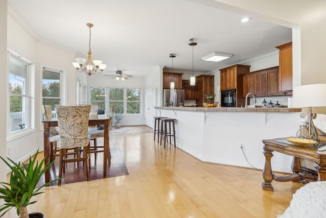 kitchen featuring kitchen peninsula, decorative light fixtures, stainless steel fridge with ice dispenser, oven, and a breakfast bar