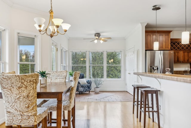 dining room with ceiling fan with notable chandelier, light hardwood / wood-style flooring, and ornamental molding