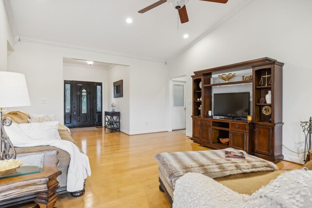 living room featuring ceiling fan, light wood-type flooring, crown molding, and vaulted ceiling