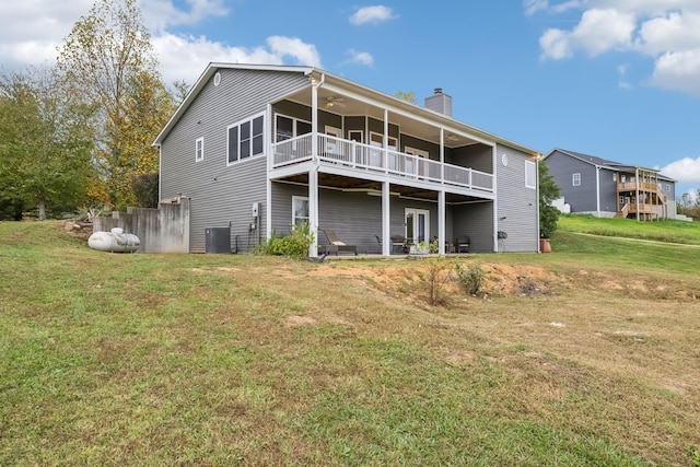 rear view of property with cooling unit and a lawn