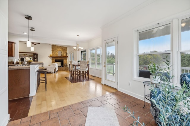 interior space featuring a stone fireplace, sink, ornamental molding, and a notable chandelier