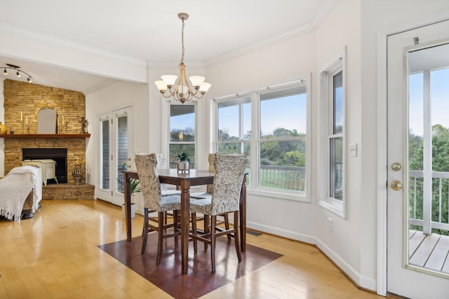 dining space featuring hardwood / wood-style floors, lofted ceiling, a fireplace, an inviting chandelier, and ornamental molding