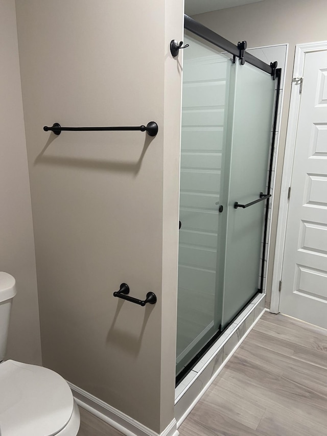 bathroom featuring wood-type flooring, an enclosed shower, and toilet