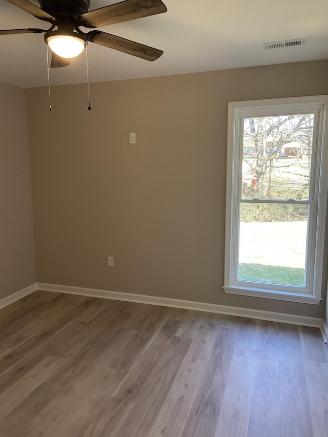 unfurnished room with hardwood / wood-style floors, a wealth of natural light, and ceiling fan