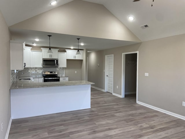 kitchen with appliances with stainless steel finishes, pendant lighting, tasteful backsplash, sink, and white cabinets