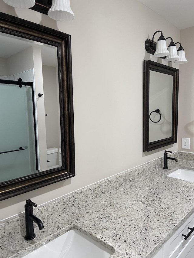 bathroom with vanity, a shower with door, and toilet