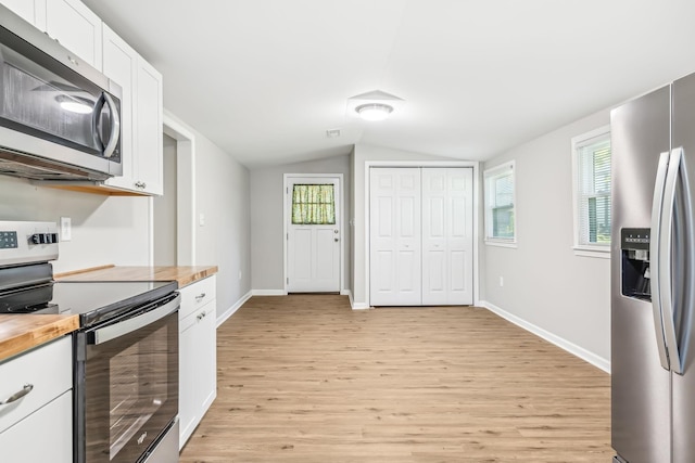 kitchen with white cabinets, light hardwood / wood-style floors, butcher block countertops, and appliances with stainless steel finishes