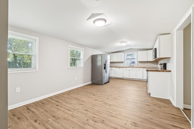 kitchen featuring light hardwood / wood-style floors, wooden counters, white cabinets, stainless steel appliances, and lofted ceiling