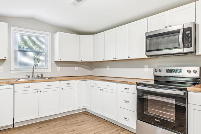 kitchen with white cabinets, stainless steel appliances, light hardwood / wood-style floors, sink, and vaulted ceiling