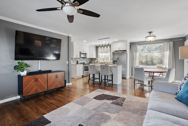 living room with dark hardwood / wood-style flooring, ceiling fan, and ornamental molding