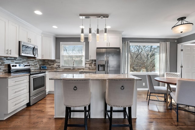 kitchen featuring a kitchen island, white cabinets, pendant lighting, and appliances with stainless steel finishes